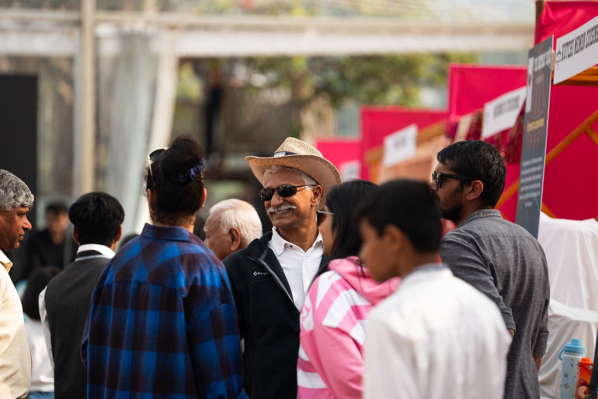 Visitors in hats moving between the food stalls