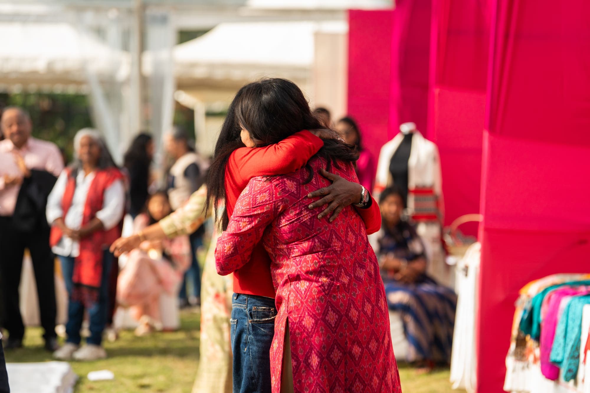 Two guests embracing on the lawn in front of the fete stalls