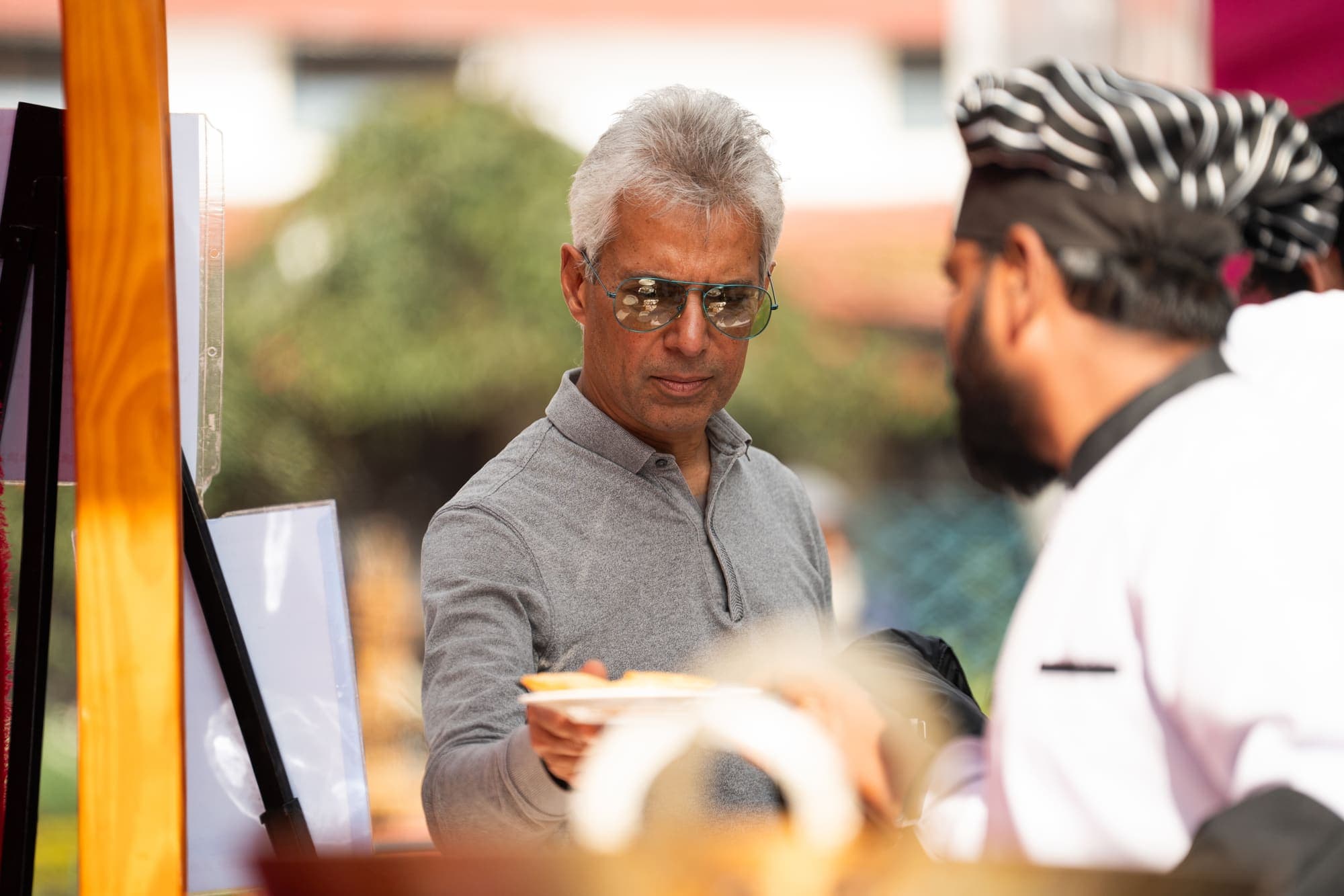 A chef handing a plate across the counter to a guest
